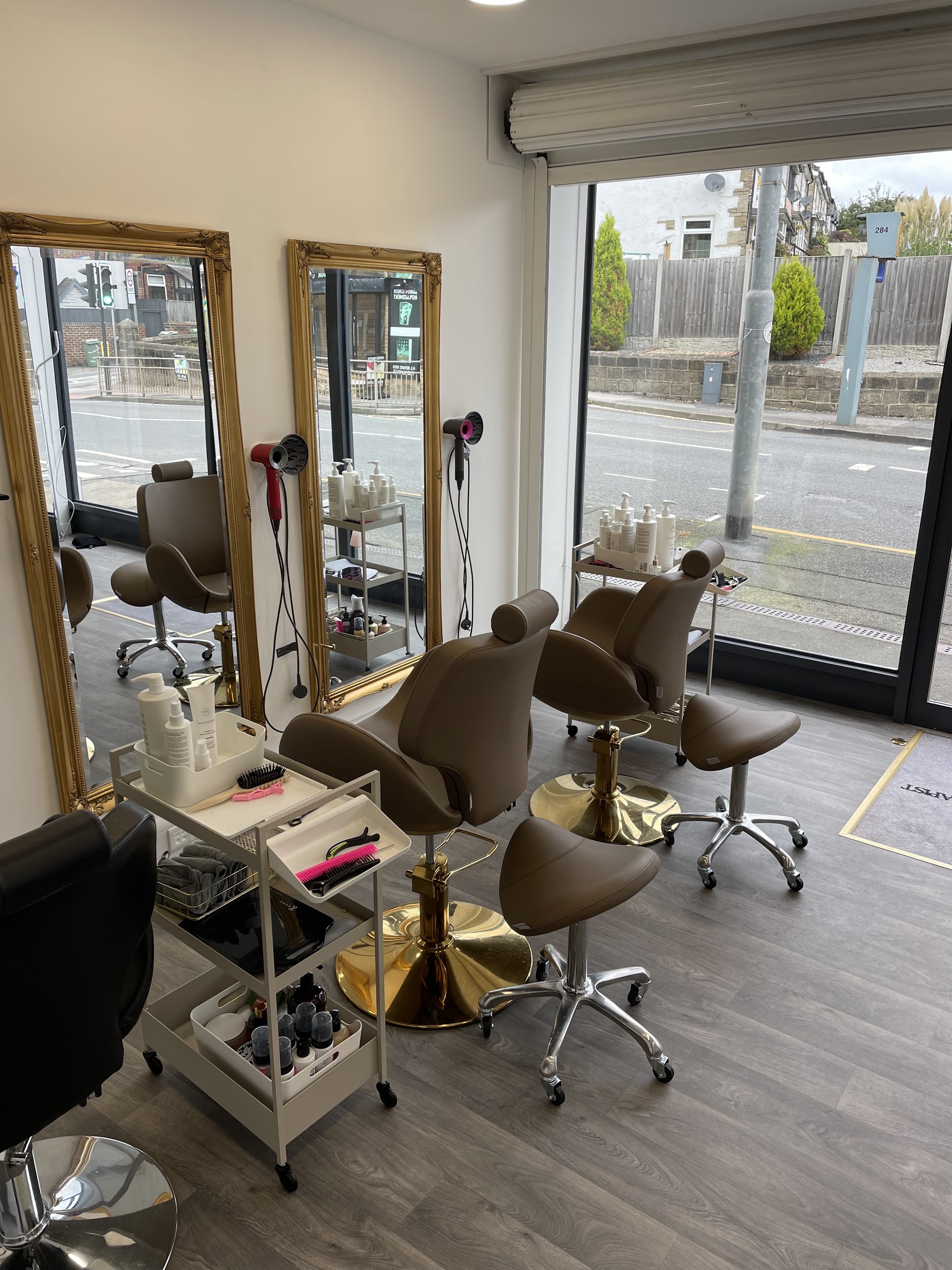 The salon's styling chairs beside tall gold-framed mirrors