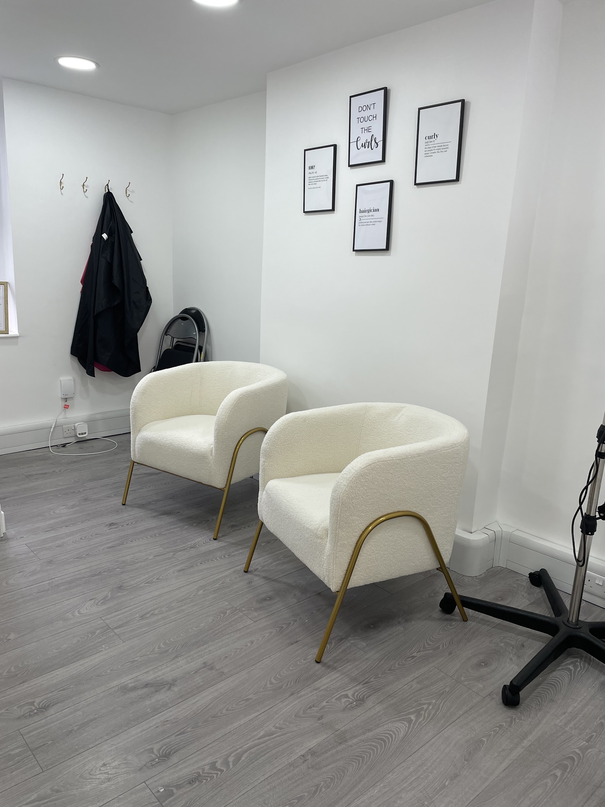Cream waiting chairs and framed curl prints inside the salon